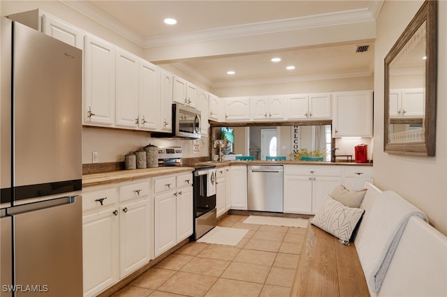 kitchen with light tile patterned flooring, white cabinetry, crown molding, and appliances with stainless steel finishes