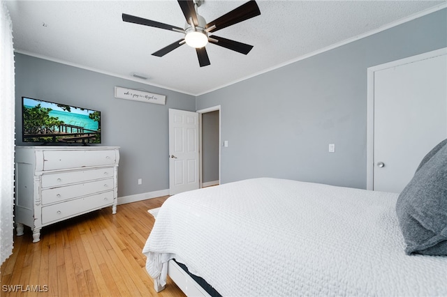 bedroom with a textured ceiling, light hardwood / wood-style flooring, ceiling fan, and ornamental molding