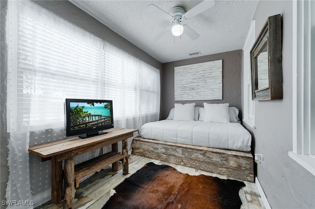 bedroom with a textured ceiling, light hardwood / wood-style floors, and ceiling fan