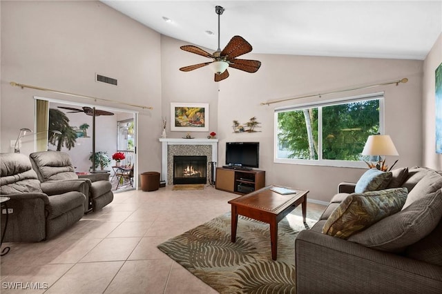 living room with light tile patterned floors, high vaulted ceiling, ceiling fan, and a tiled fireplace