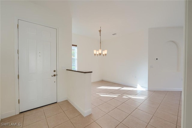 entryway with light tile patterned flooring and an inviting chandelier