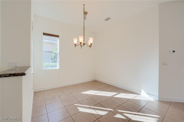 tiled spare room with a chandelier