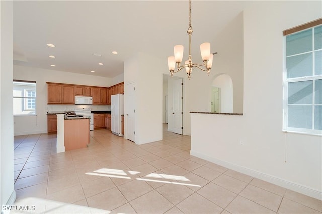 kitchen featuring hanging light fixtures, a kitchen island, a notable chandelier, white appliances, and light tile patterned floors