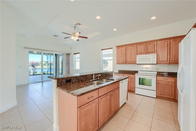 kitchen with light tile patterned flooring, white appliances, dark stone counters, and sink