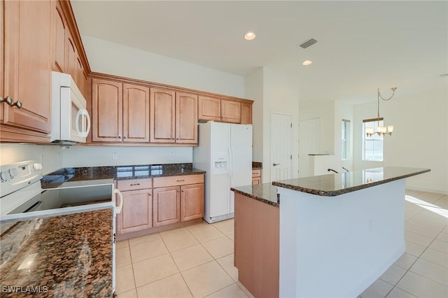 kitchen with a center island, an inviting chandelier, dark stone counters, white appliances, and light tile patterned floors