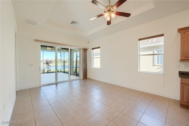 tiled empty room with a tray ceiling and ceiling fan