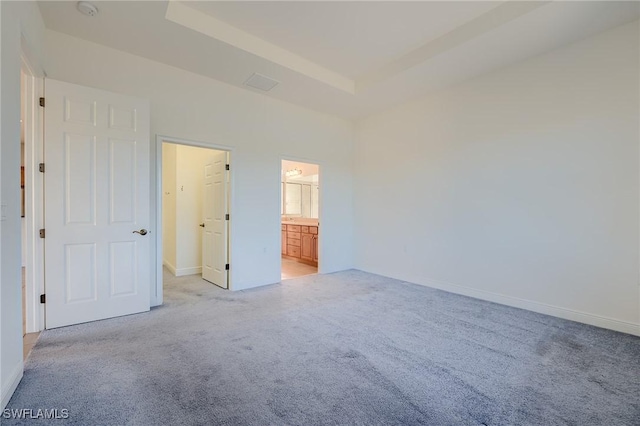 unfurnished bedroom featuring light colored carpet and ensuite bath