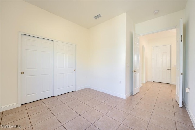 unfurnished bedroom featuring light tile patterned floors and a closet