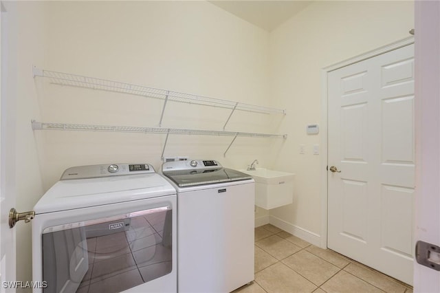 clothes washing area featuring washer and clothes dryer, light tile patterned floors, and sink