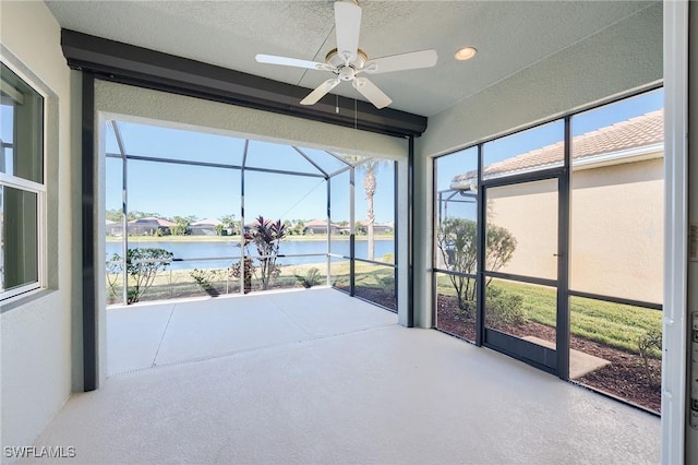 sunroom / solarium with ceiling fan and a water view