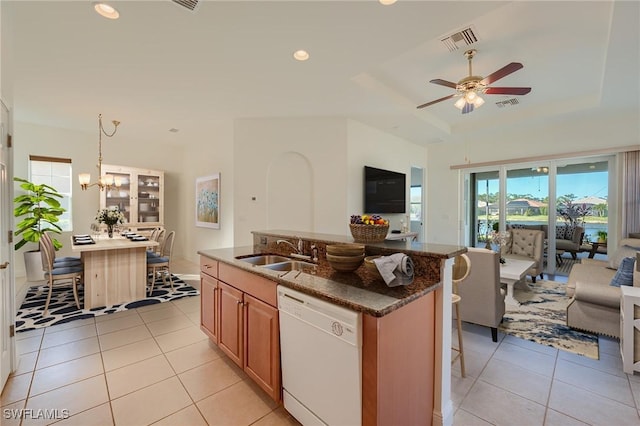 kitchen featuring a kitchen island with sink, white dishwasher, a kitchen breakfast bar, hanging light fixtures, and sink