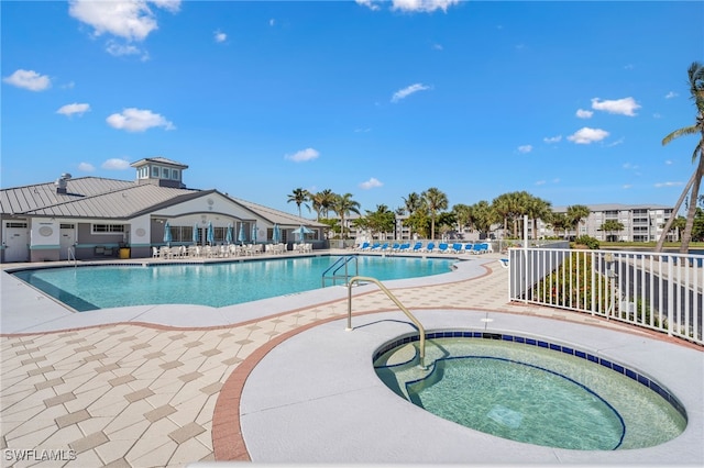 community pool with a patio area, fence, and a hot tub