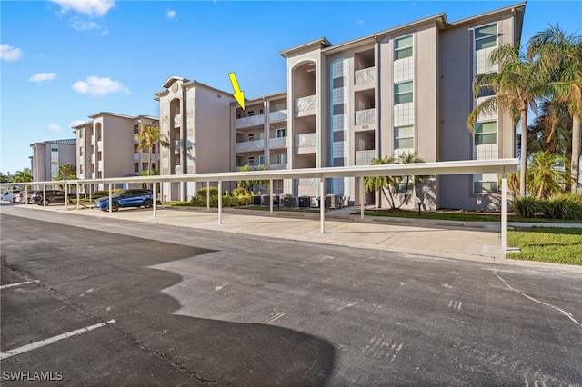 view of property featuring covered and uncovered parking