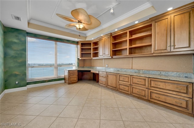 unfurnished office featuring visible vents, a tray ceiling, ornamental molding, built in desk, and a ceiling fan