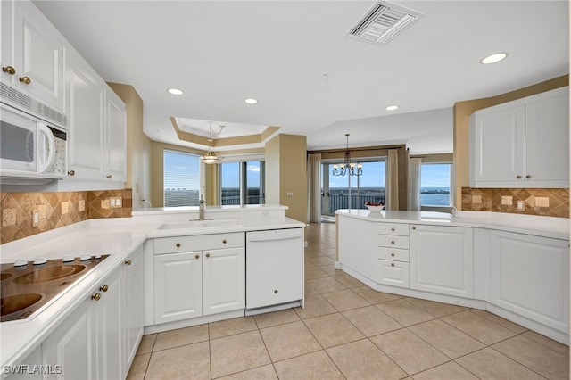 kitchen featuring white appliances, a peninsula, visible vents, and a sink