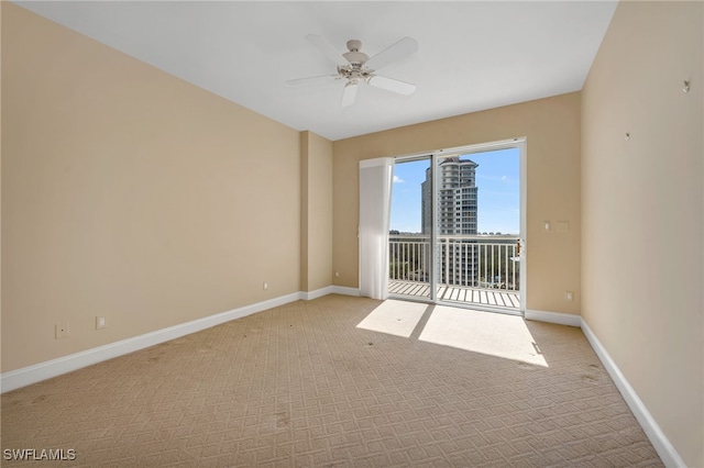 spare room with baseboards, light carpet, and a ceiling fan