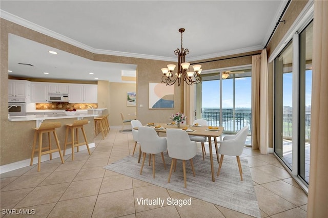 dining area with a water view, ornamental molding, light tile patterned flooring, baseboards, and a chandelier