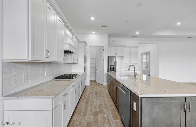 kitchen with sink, white cabinets, a spacious island, and custom range hood