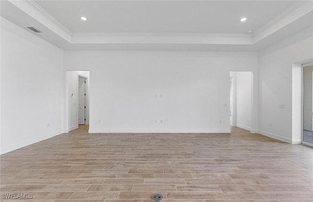 unfurnished room featuring a tray ceiling, light hardwood / wood-style flooring, and crown molding