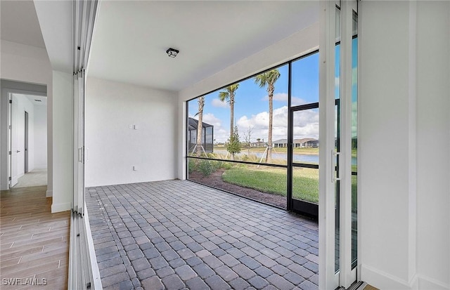 unfurnished sunroom featuring a water view