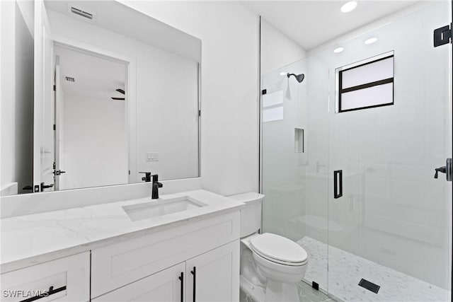 bathroom with ceiling fan, vanity, a shower with shower door, and toilet