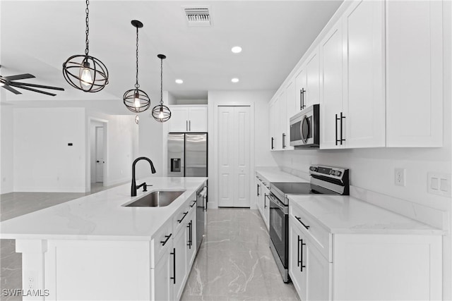 kitchen with a kitchen island with sink, white cabinets, sink, decorative light fixtures, and stainless steel appliances