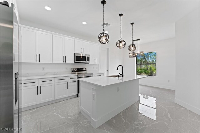 kitchen with sink, stainless steel appliances, pendant lighting, a center island with sink, and white cabinets