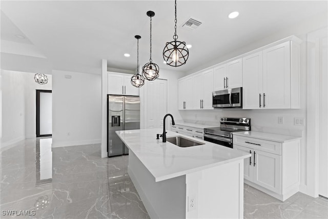 kitchen with appliances with stainless steel finishes, sink, a center island with sink, decorative light fixtures, and white cabinets