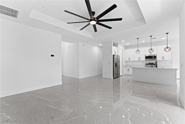 unfurnished living room featuring a tray ceiling and ceiling fan