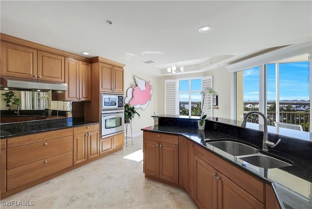 kitchen with sink, dark stone counters, a notable chandelier, and appliances with stainless steel finishes