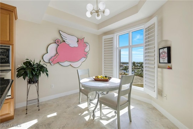 dining area with a raised ceiling and a notable chandelier