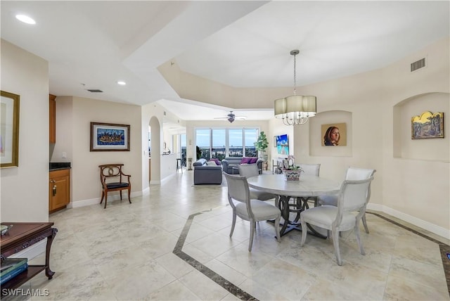 dining space featuring ceiling fan with notable chandelier