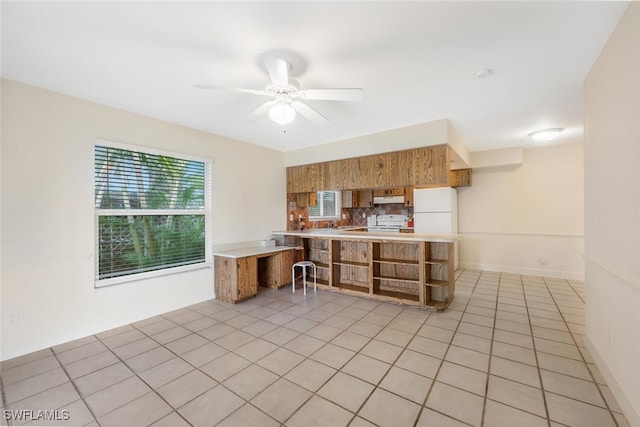 kitchen with white appliances, decorative backsplash, ceiling fan, light tile patterned floors, and kitchen peninsula