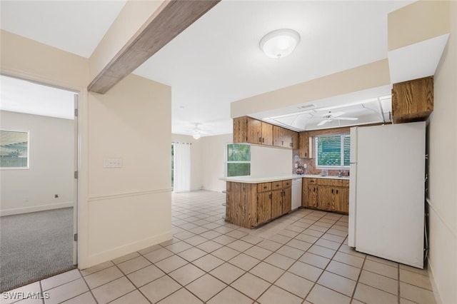 kitchen with ceiling fan, sink, kitchen peninsula, white appliances, and light carpet