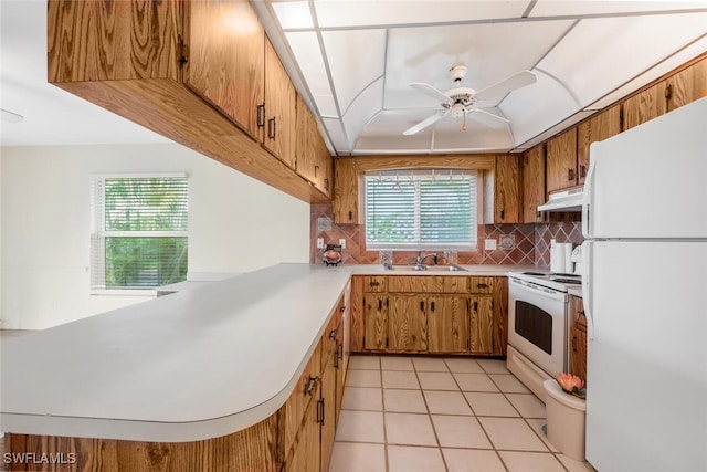 kitchen featuring kitchen peninsula, backsplash, white appliances, ceiling fan, and light tile patterned floors