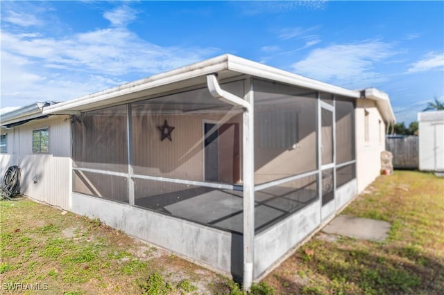 view of side of property with a sunroom and a lawn