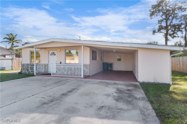 view of front of property featuring covered porch, a front lawn, and a carport