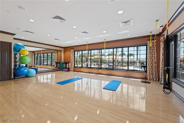 workout room featuring light wood-type flooring and ornamental molding