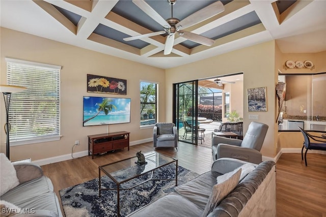 living room featuring ceiling fan, a healthy amount of sunlight, wood-type flooring, and coffered ceiling