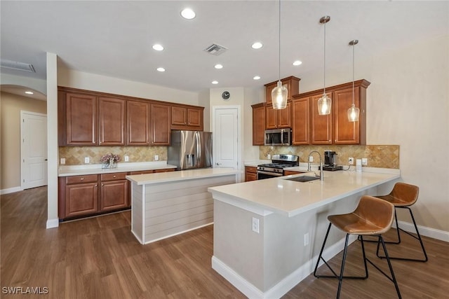 kitchen featuring pendant lighting, a breakfast bar, sink, kitchen peninsula, and stainless steel appliances