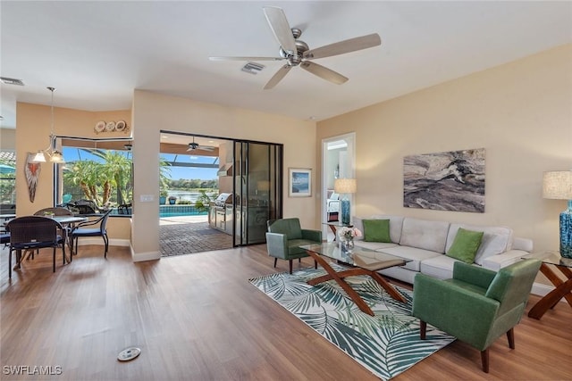 living room featuring wood-type flooring and ceiling fan with notable chandelier