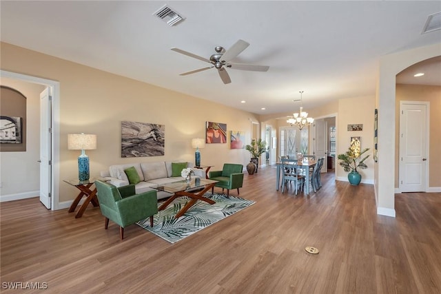 living room with ceiling fan with notable chandelier and hardwood / wood-style flooring