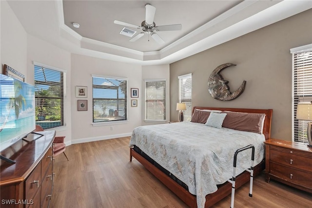 bedroom featuring light wood-type flooring, a tray ceiling, and ceiling fan