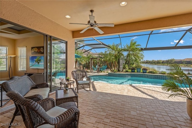 view of swimming pool featuring a water view, a patio area, ceiling fan, and a lanai