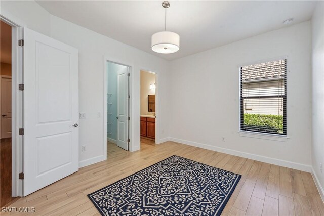 8464 Palacio Ter W, Naples, FL 34114 - unfurnished bedroom with light wood finished floors, baseboards, and ensuite bath