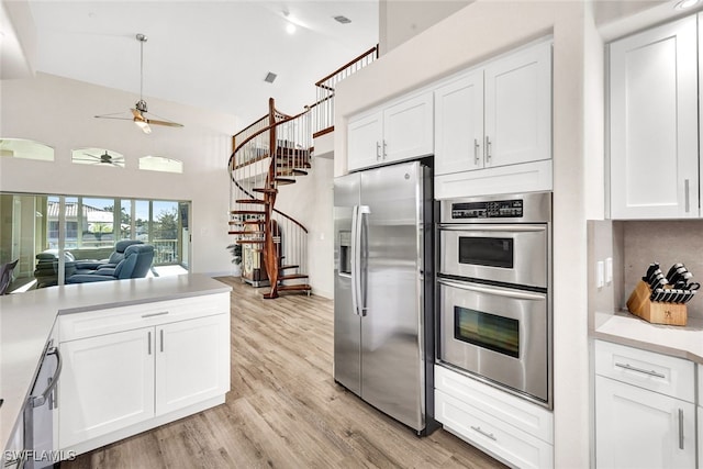 kitchen with ceiling fan, stainless steel appliances, tasteful backsplash, white cabinets, and light hardwood / wood-style flooring