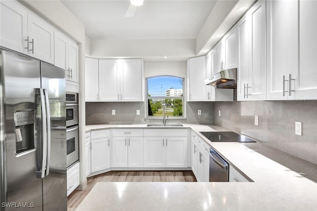 kitchen with backsplash, sink, hardwood / wood-style flooring, appliances with stainless steel finishes, and white cabinets