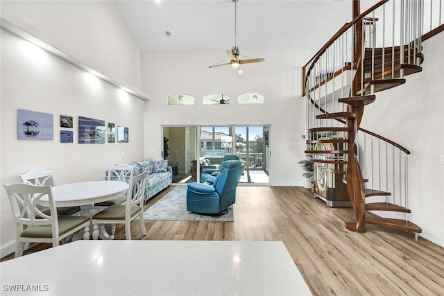 living room featuring ceiling fan, light hardwood / wood-style flooring, and a high ceiling