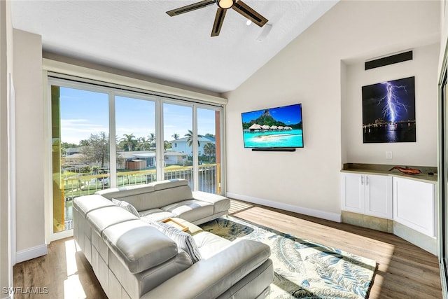 living room featuring ceiling fan, vaulted ceiling, a textured ceiling, and light hardwood / wood-style flooring