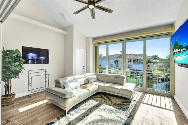 living room with ceiling fan, wood-type flooring, lofted ceiling, and a textured ceiling